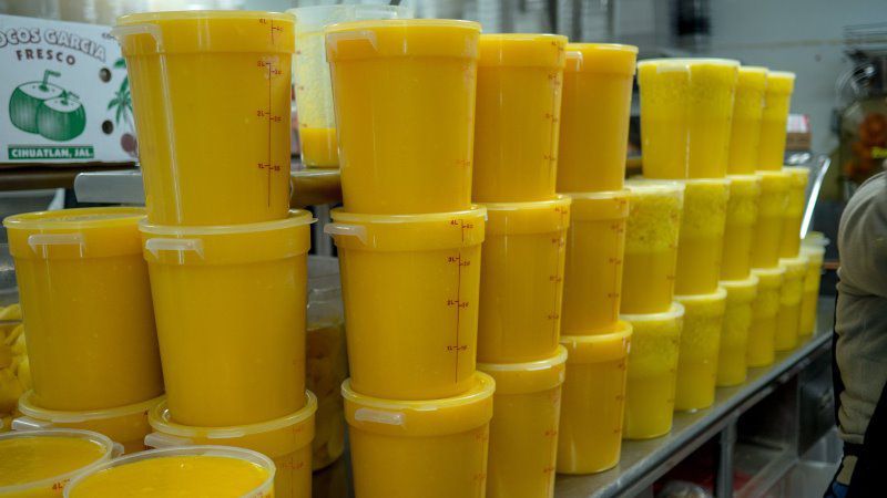 Yellow liquid in stacked plastic containers at a store, likely for sale.