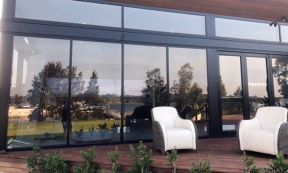 Two chairs are sitting on a deck in front of a building with a lot of windows.