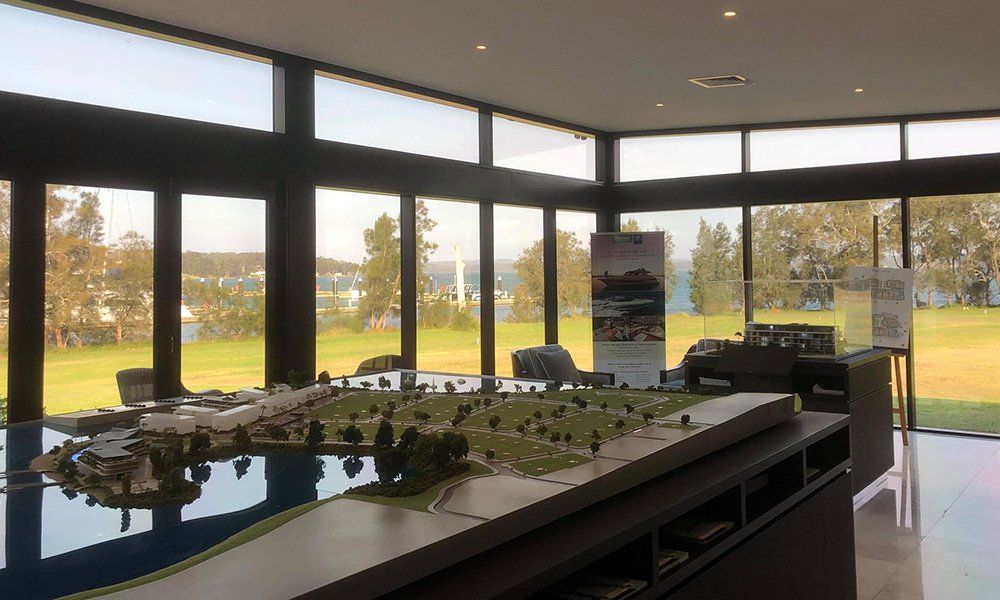 A model of a city is on a table in a room with lots of windows.