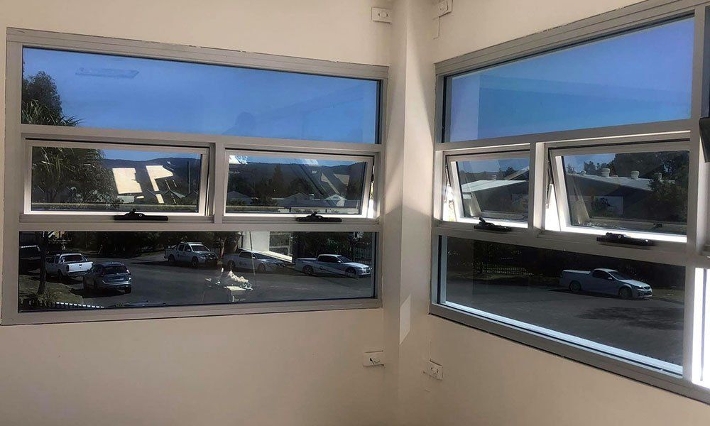 A room with a lot of windows and a parking lot in the background.