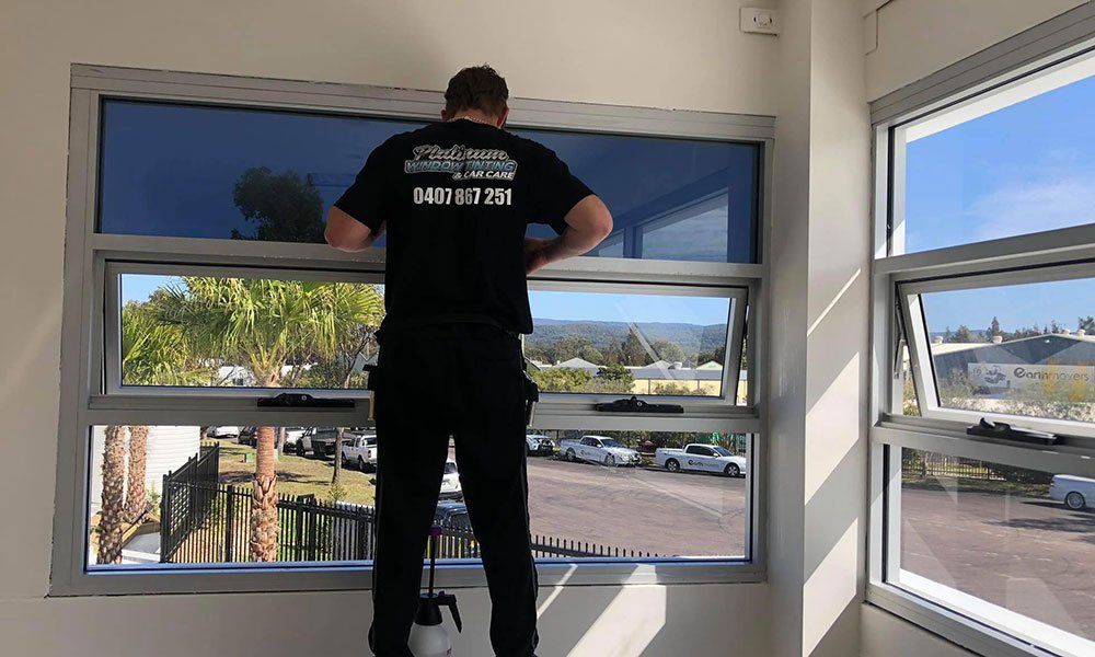 A man in a black shirt is standing in front of a window.