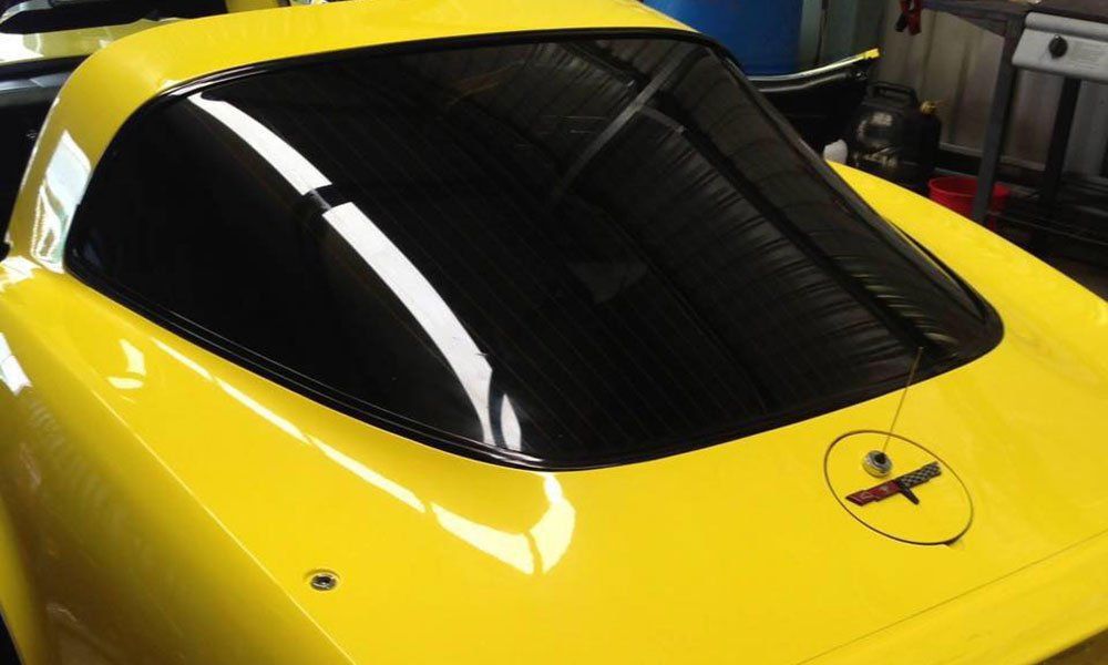 A yellow sports car with a small airplane on the back