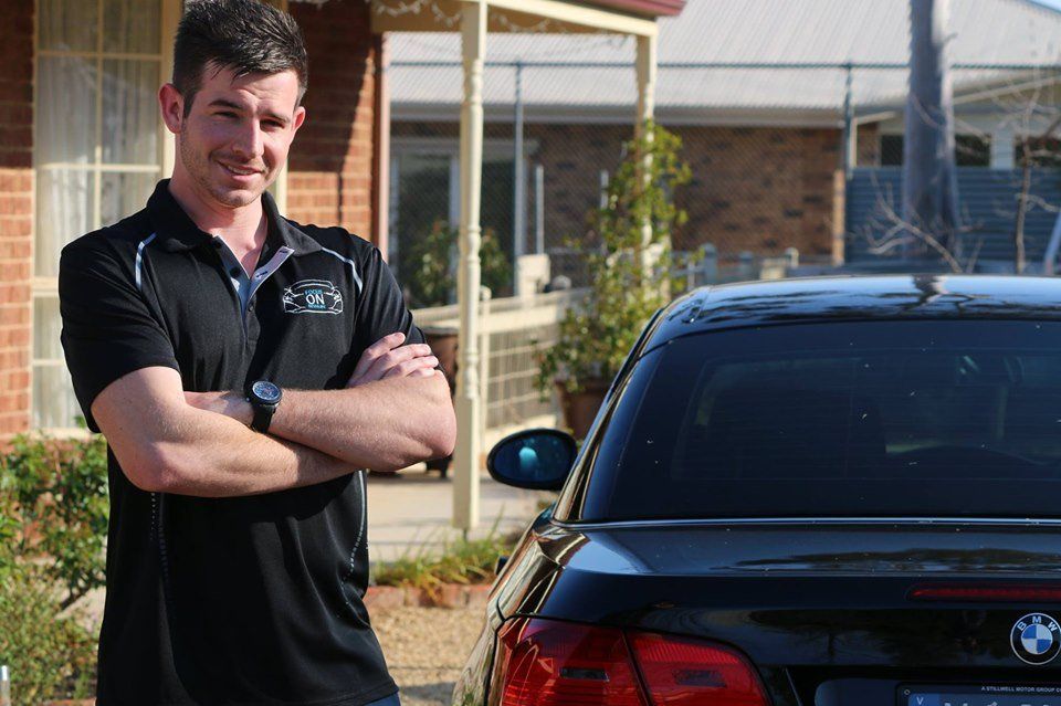 A man is standing in front of a black bmw car.