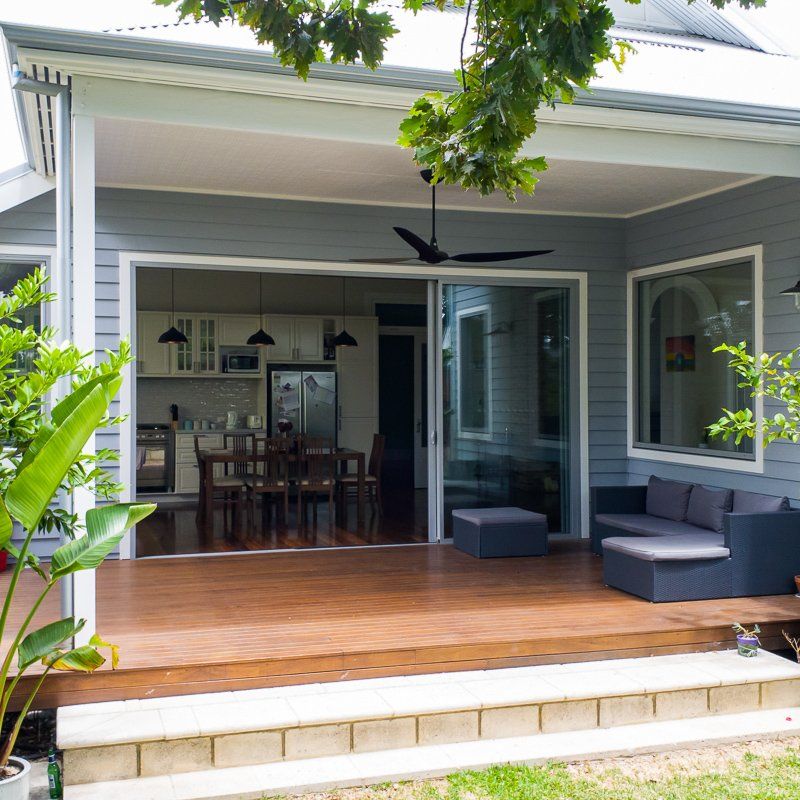 Deck with sliding glass doors opening to kitchen/dining area. Gray siding, dark furniture, wooden deck.