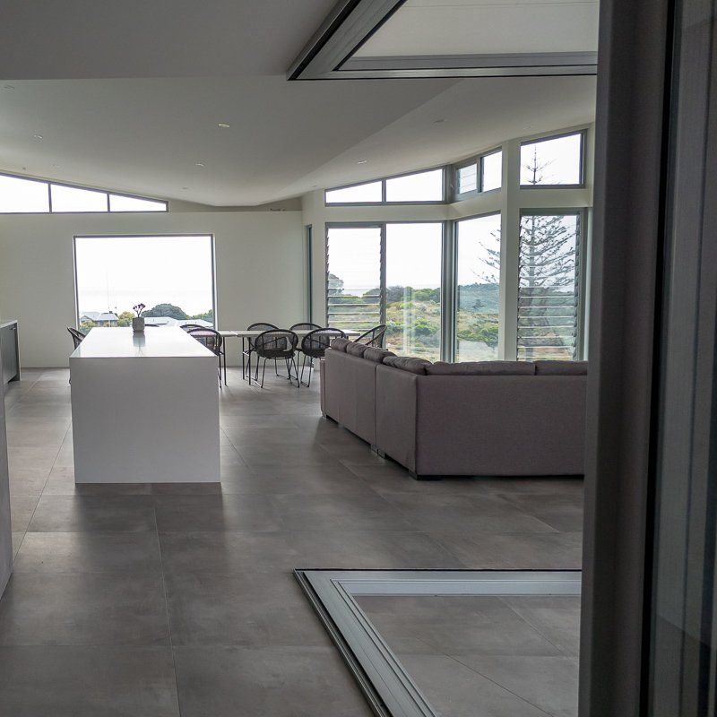 Modern open-plan living space with large windows and a view of the outdoors. Features kitchen island, seating area.