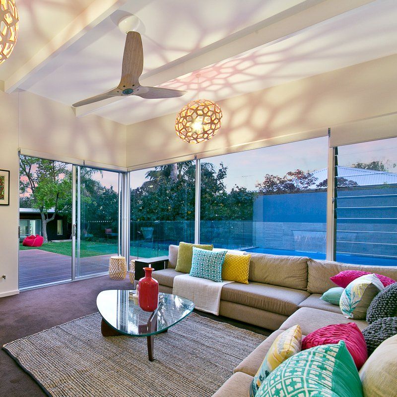 Living room with large sectional sofa and glass doors overlooking a pool and yard. Beige, colorful pillows.