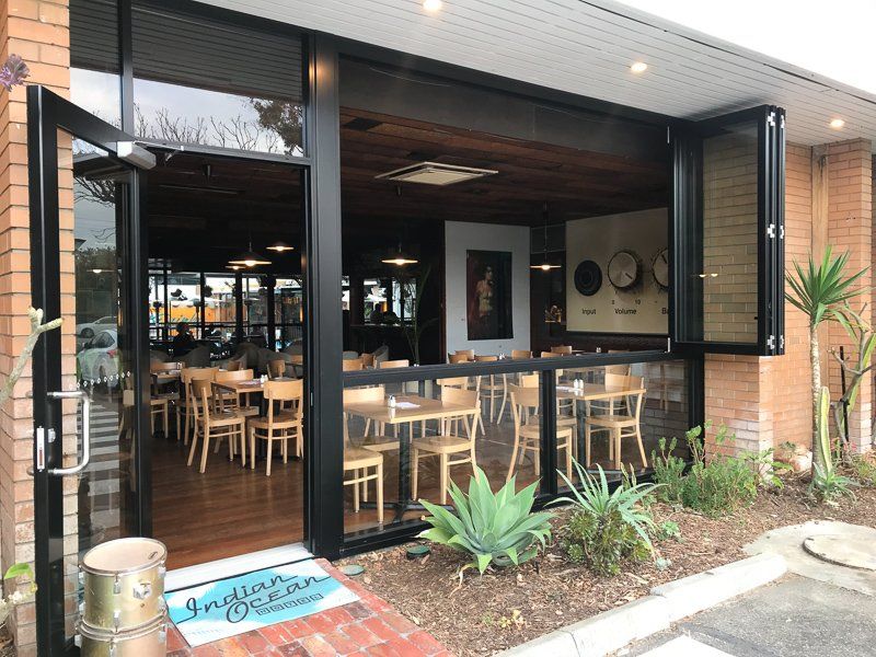 Exterior of Indian Ocean Restaurant with open doors, tables, and plants.
