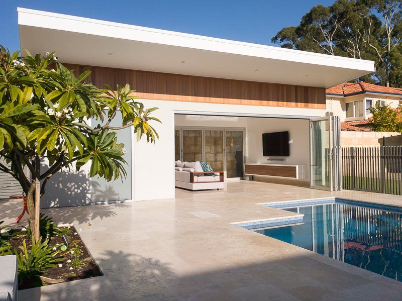Modern home exterior with pool. White walls, wooden accent, open to patio with pool. Sunny day.