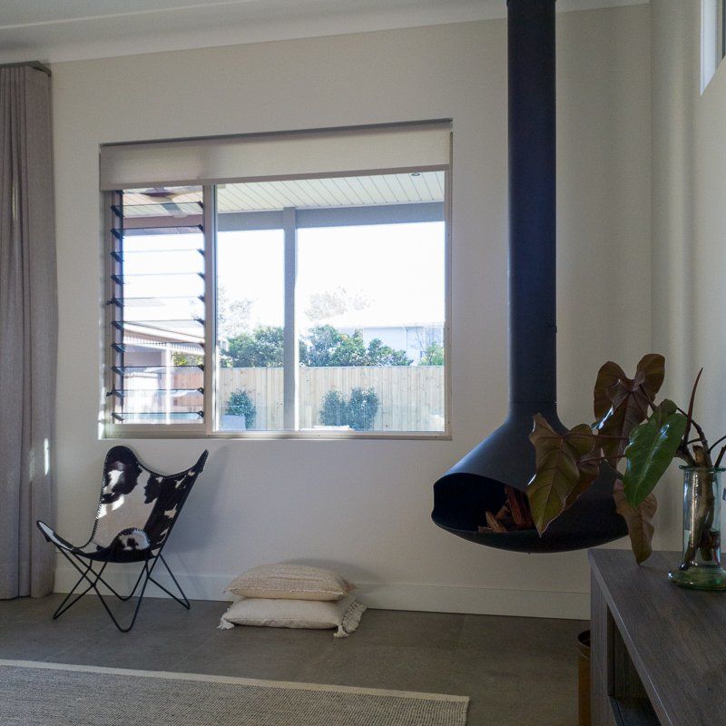 Modern living room with hanging fireplace, chair, window, and plants.