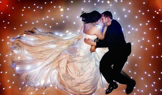 bride and groom laying on starry light up dance floor