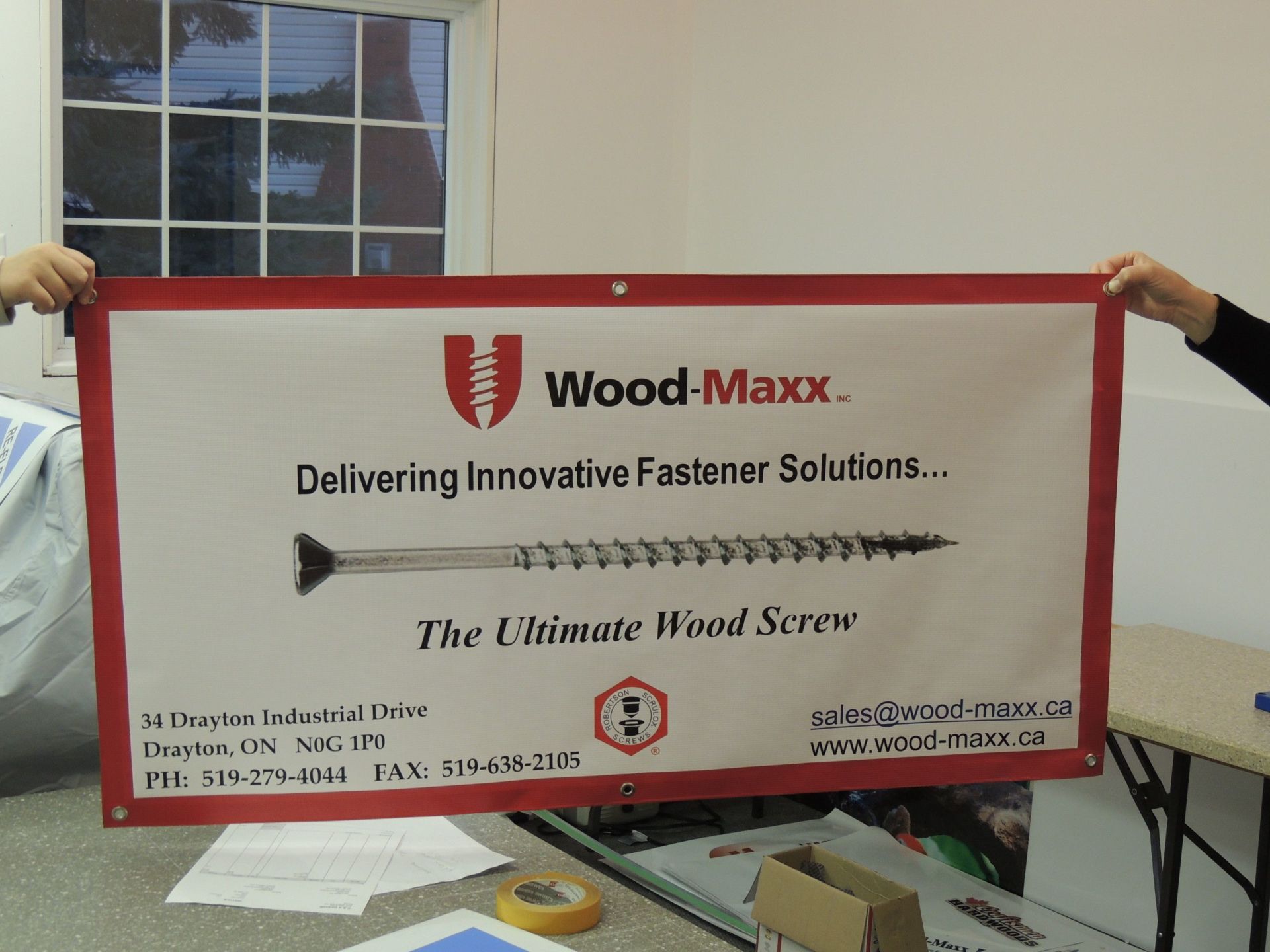 Banner held by two people, red border, reads 