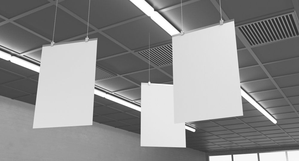 Three blank rectangular posters hanging from a drop ceiling.