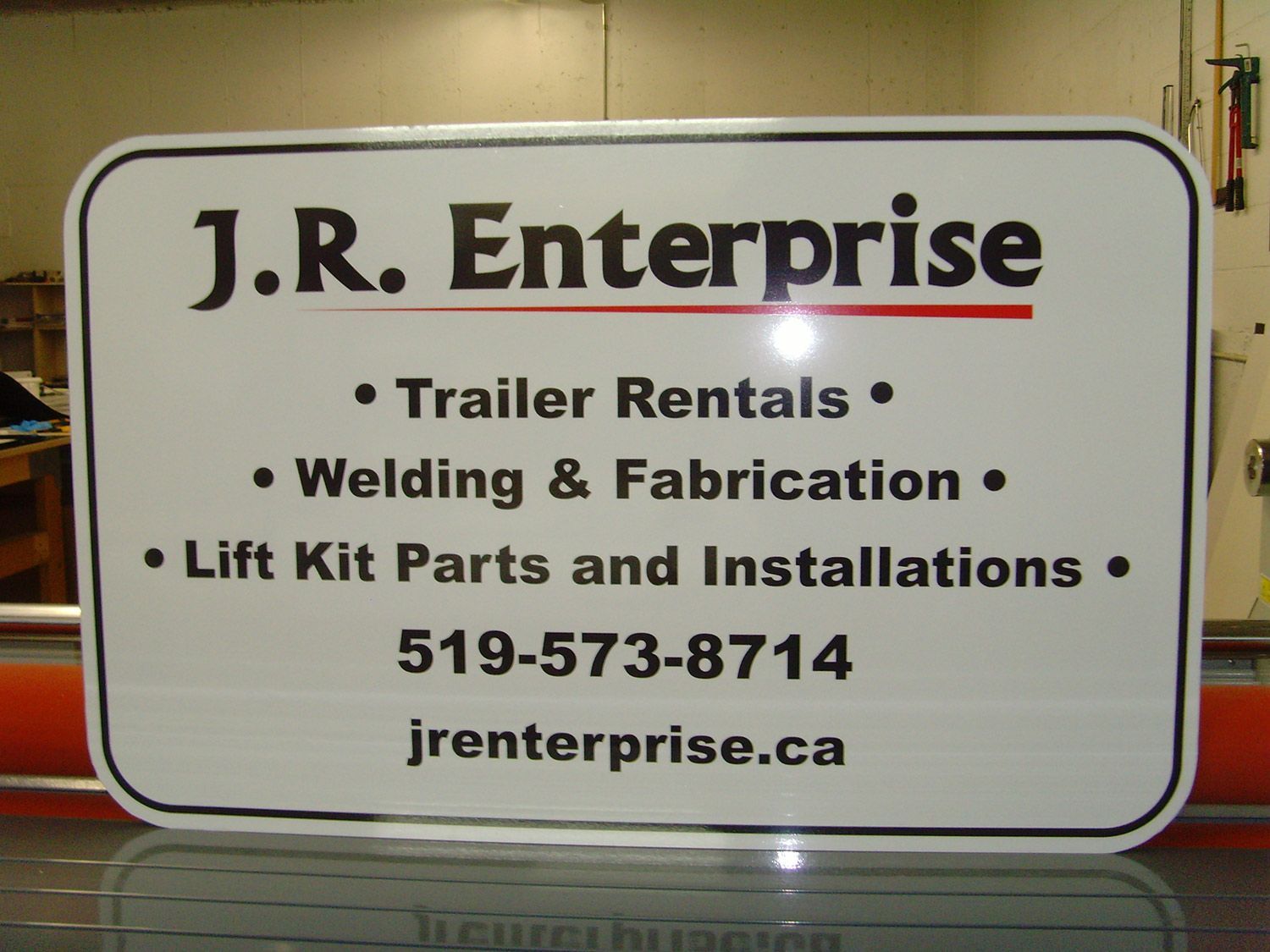Sign for J.R. Enterprise, advertising trailer rentals, welding, and lift kit services. White background, black text.