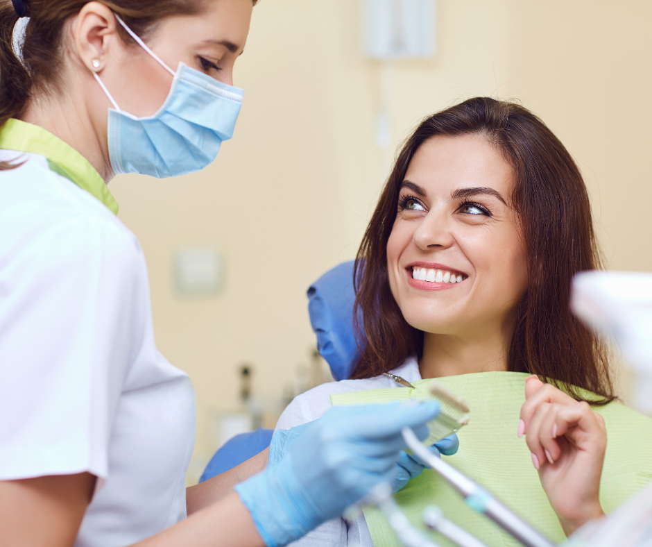 Dentist examining a patient's teeth; both smiling in a dental office.