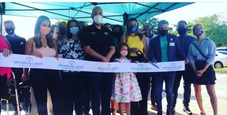 People cutting a ribbon at an outdoor event labeled 