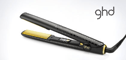 Auf einer weißen Oberfläche steht ein schwarz-goldener Haarglätter von ghd.