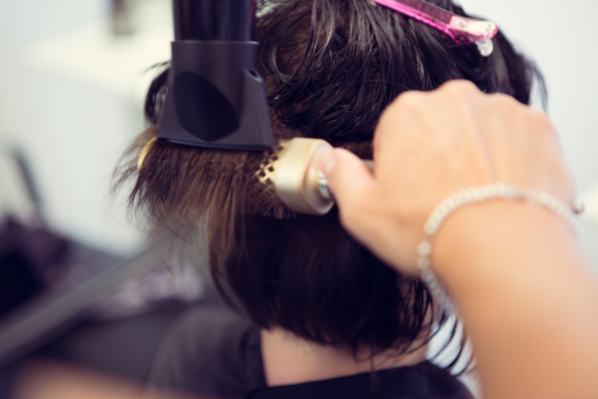 Eine Frau lässt sich von einem Friseur die Haare föhnen.