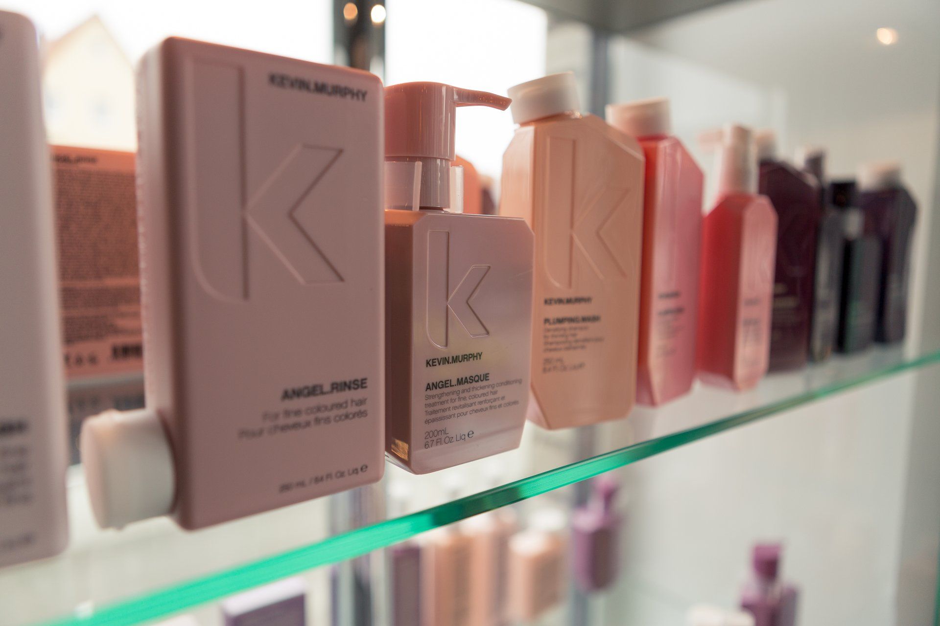 Eine Reihe von Flaschen mit Haarpflegeprodukten von Kevin Murphy auf einem Glasregal