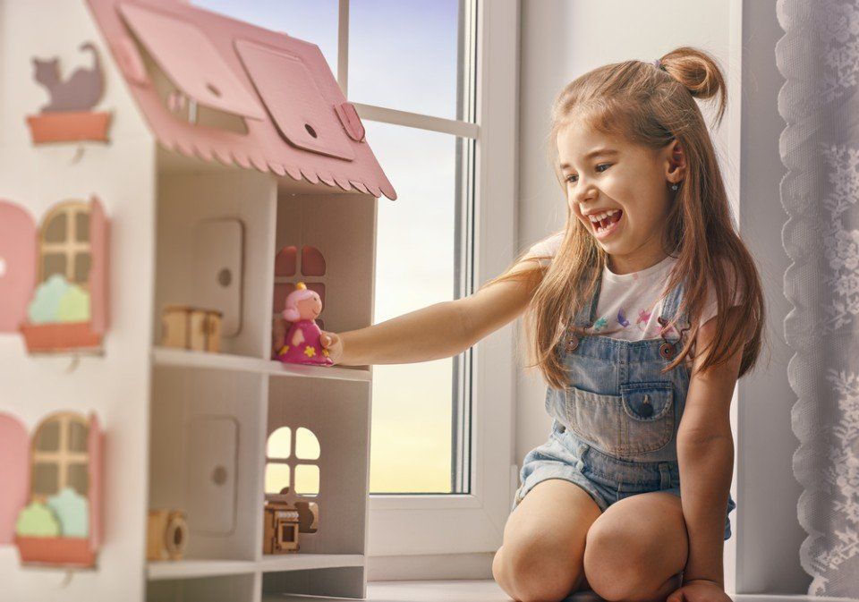 bambina che gioca con la casa delle bambole