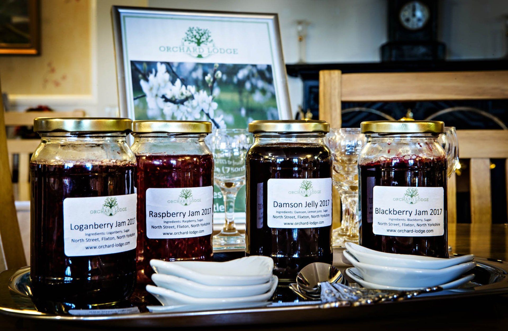 Four jars of jam are sitting on a tray on a table.