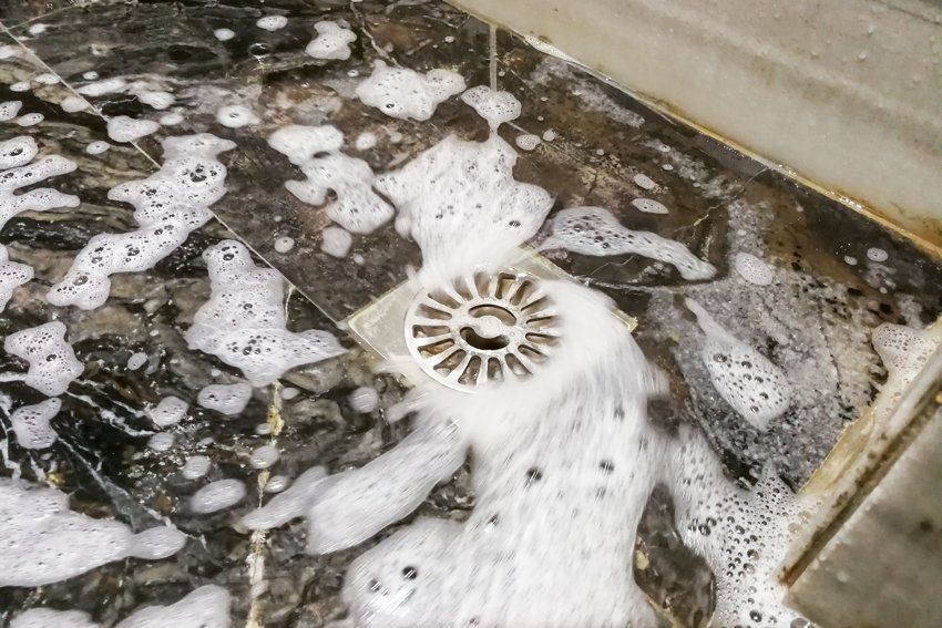 Soap Foam And Water Flowing Into Bathroom Drainage Hole — Elkhart, IN — Roto-Rooter Sewer - Drain Services drain cleaning Elkhart Indiana