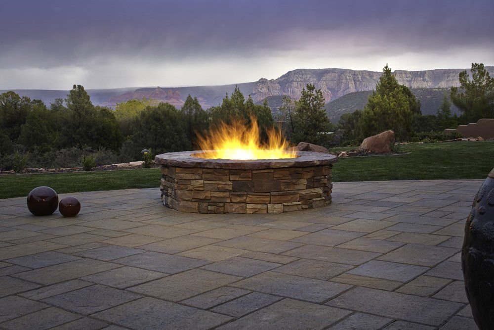 A fire pit is lit up on a patio with mountains in the background.