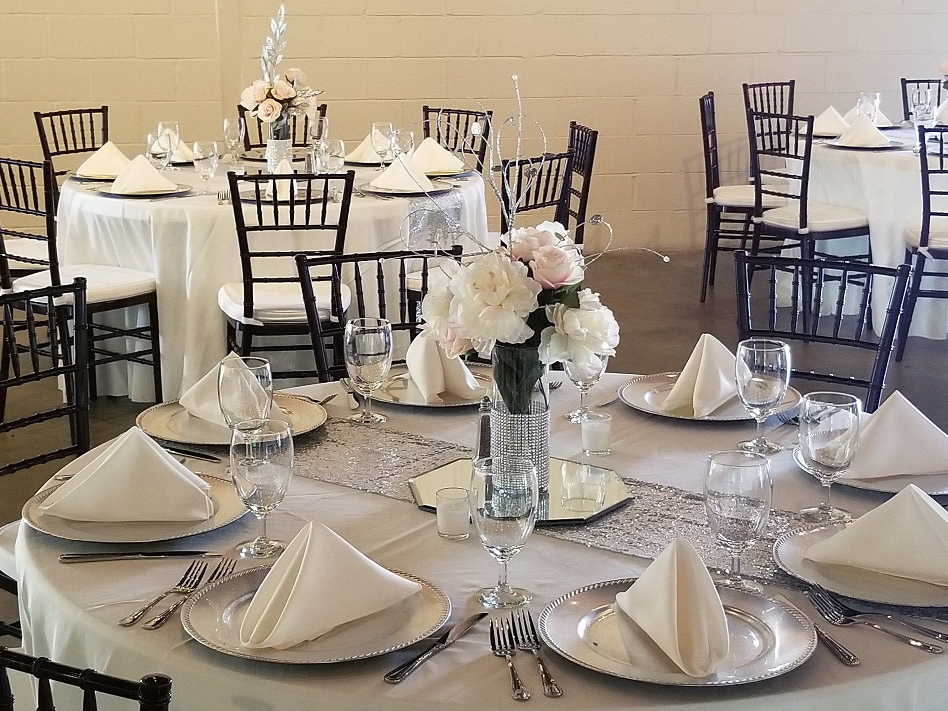 table setting with white and silver decor with floral centerpiece