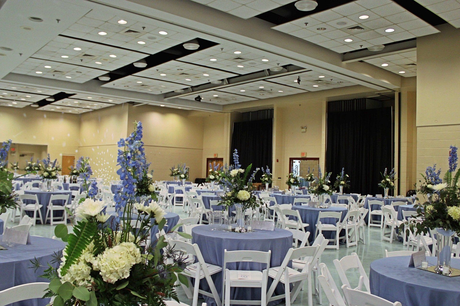 room set up with round tables in a blue and white decor and floral centerpieces