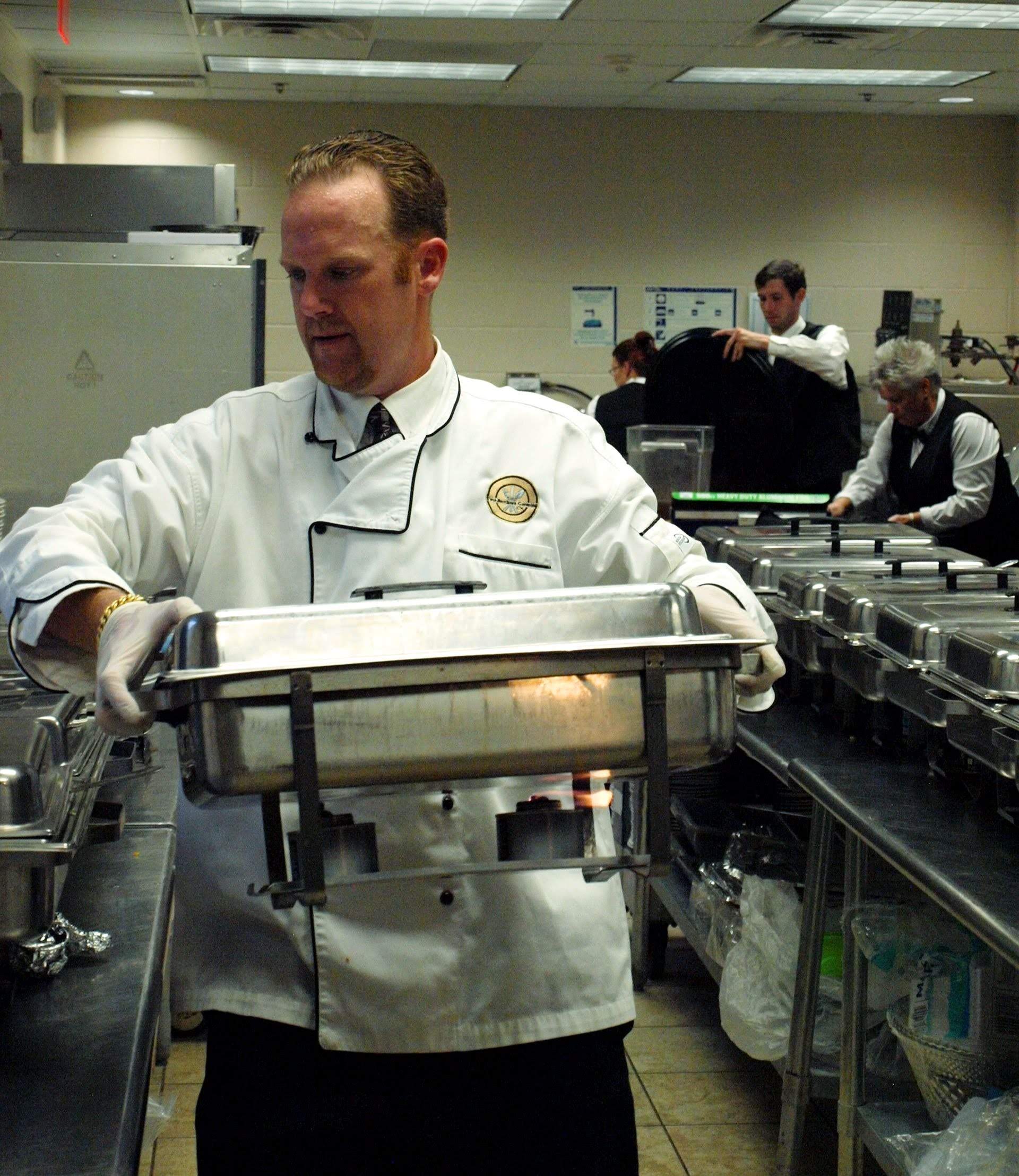 a male caterer carrying a buffet pan