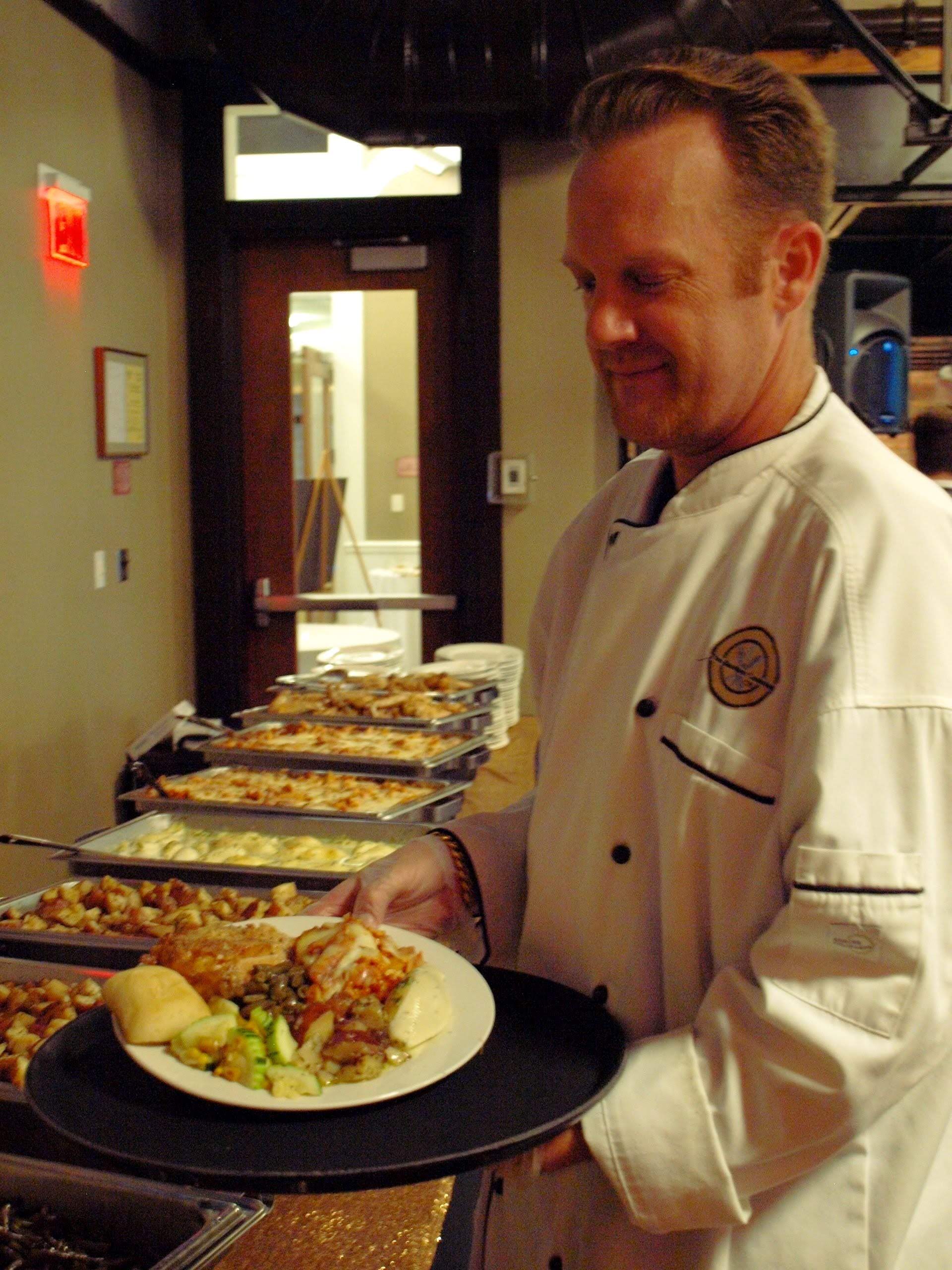 male caterer carrying a plate of food on a tray