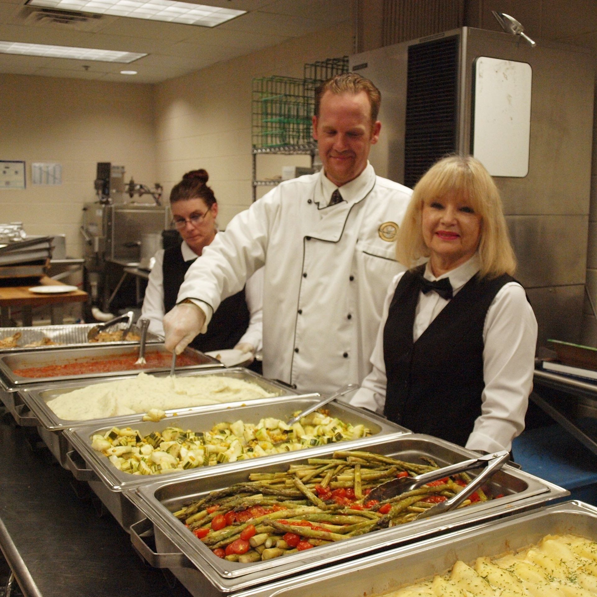 male and felmale caterer standing in front of buffet
