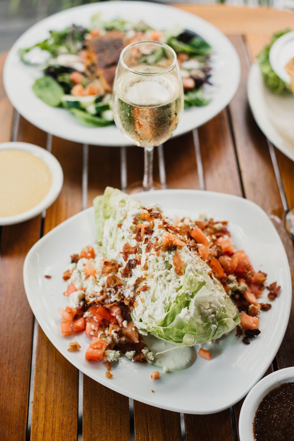 A table topped with plates of food and a glass of wine.