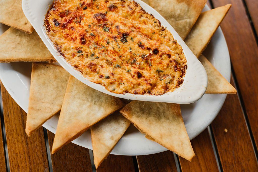 A white plate topped with tortilla chips and a bowl of dip.