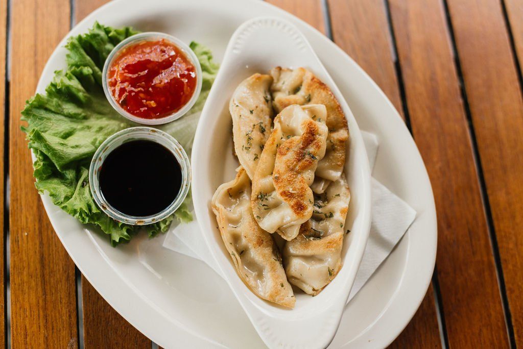 A white plate topped with dumplings and sauce on a wooden table.