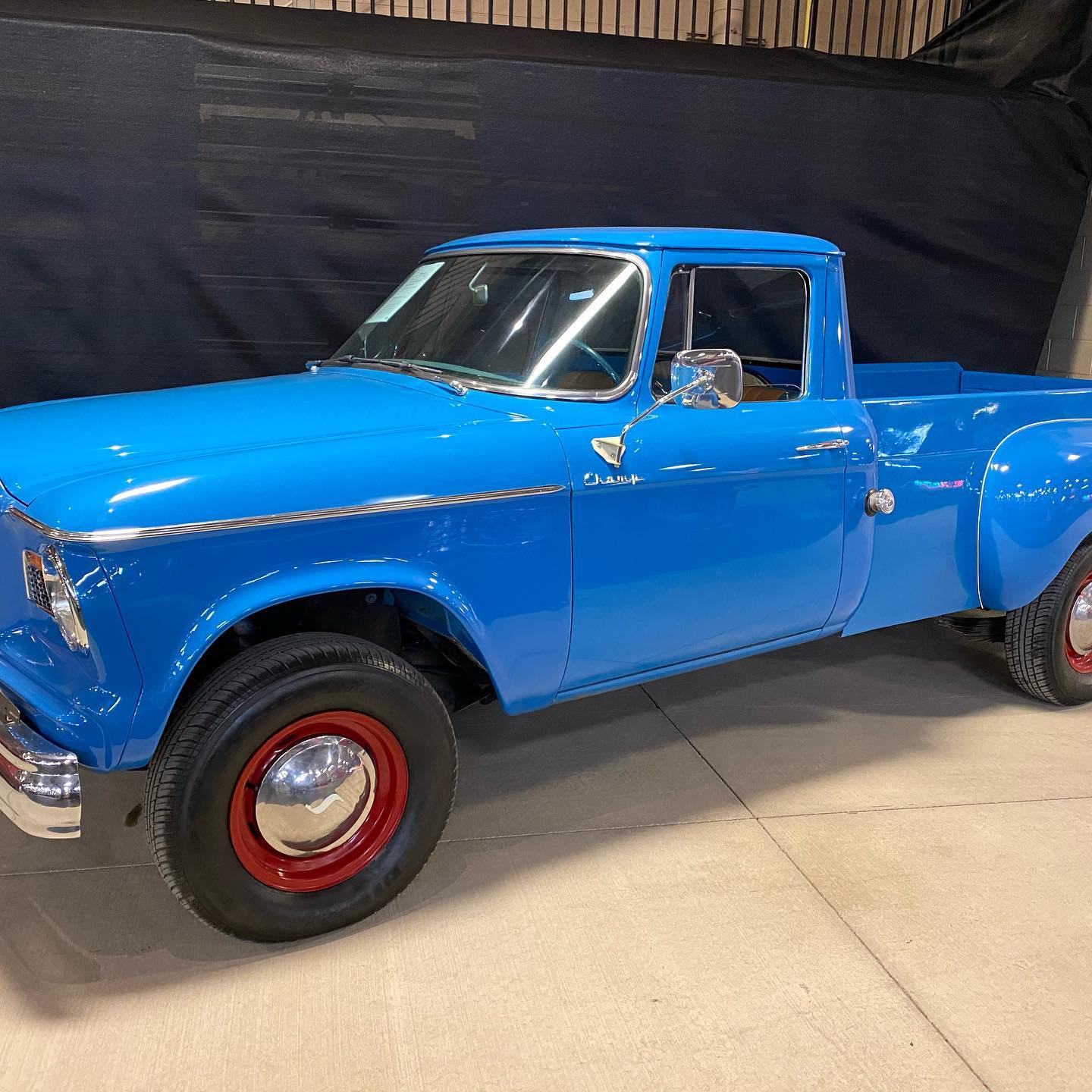 a blue truck with red wheels parked in a garage .