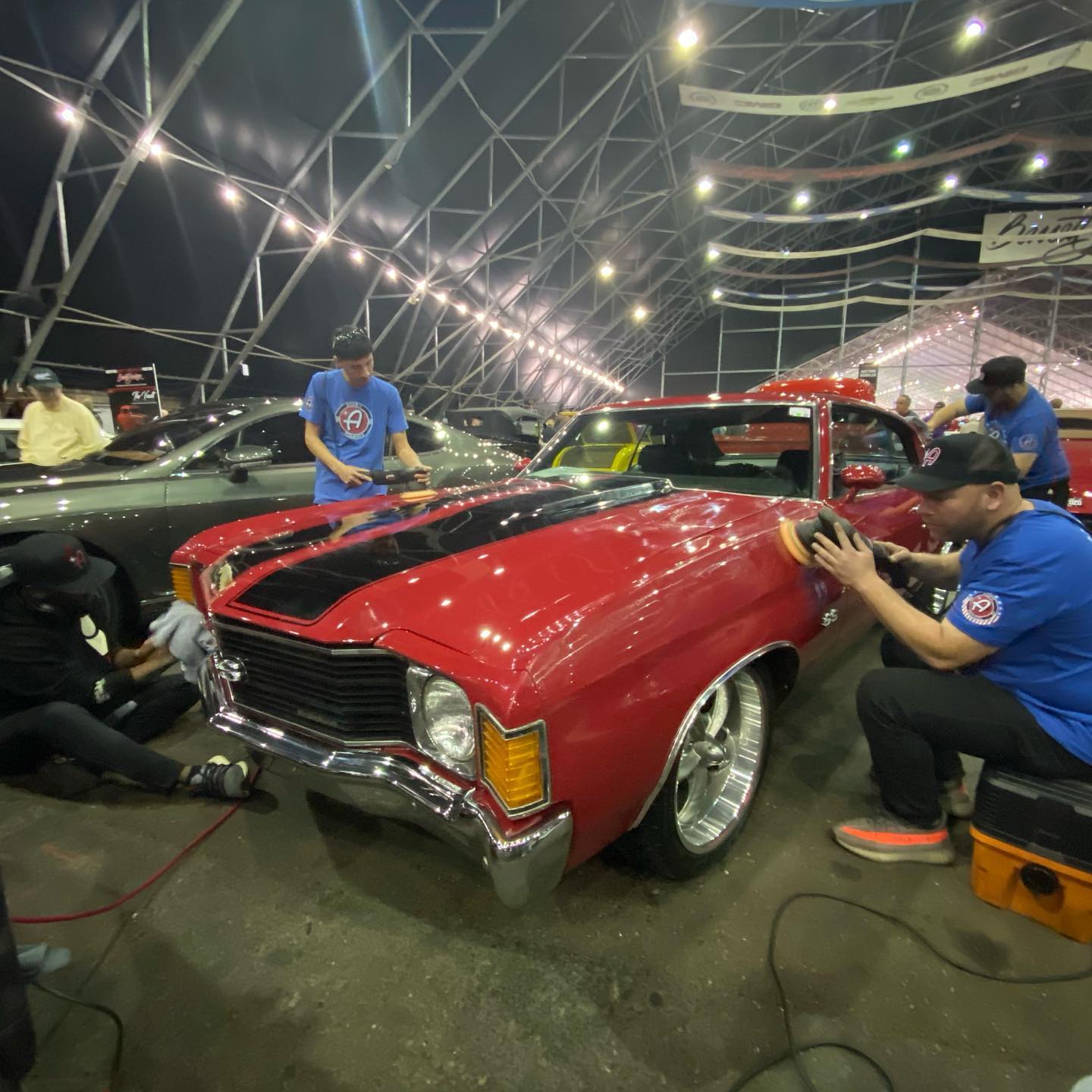 a group of men working on detailing a red car