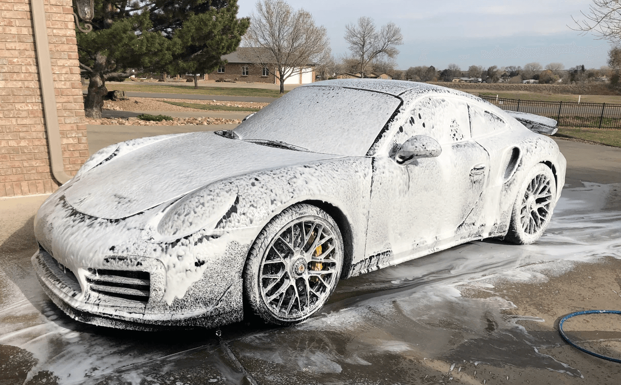 a porsche covered in foam in a driveway .