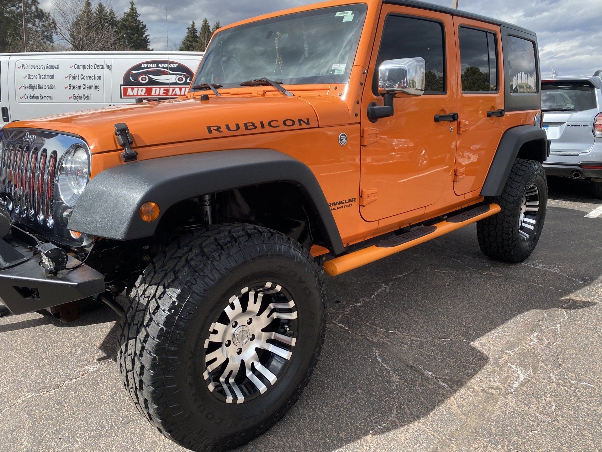 an orange jeep is parked in a parking lot .