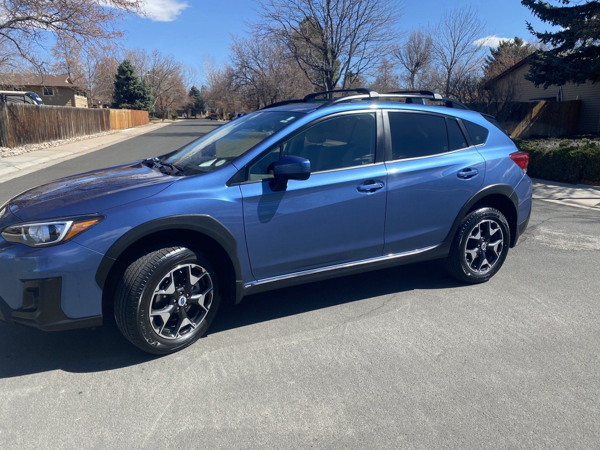 a blue suv is parked on the side of the road .