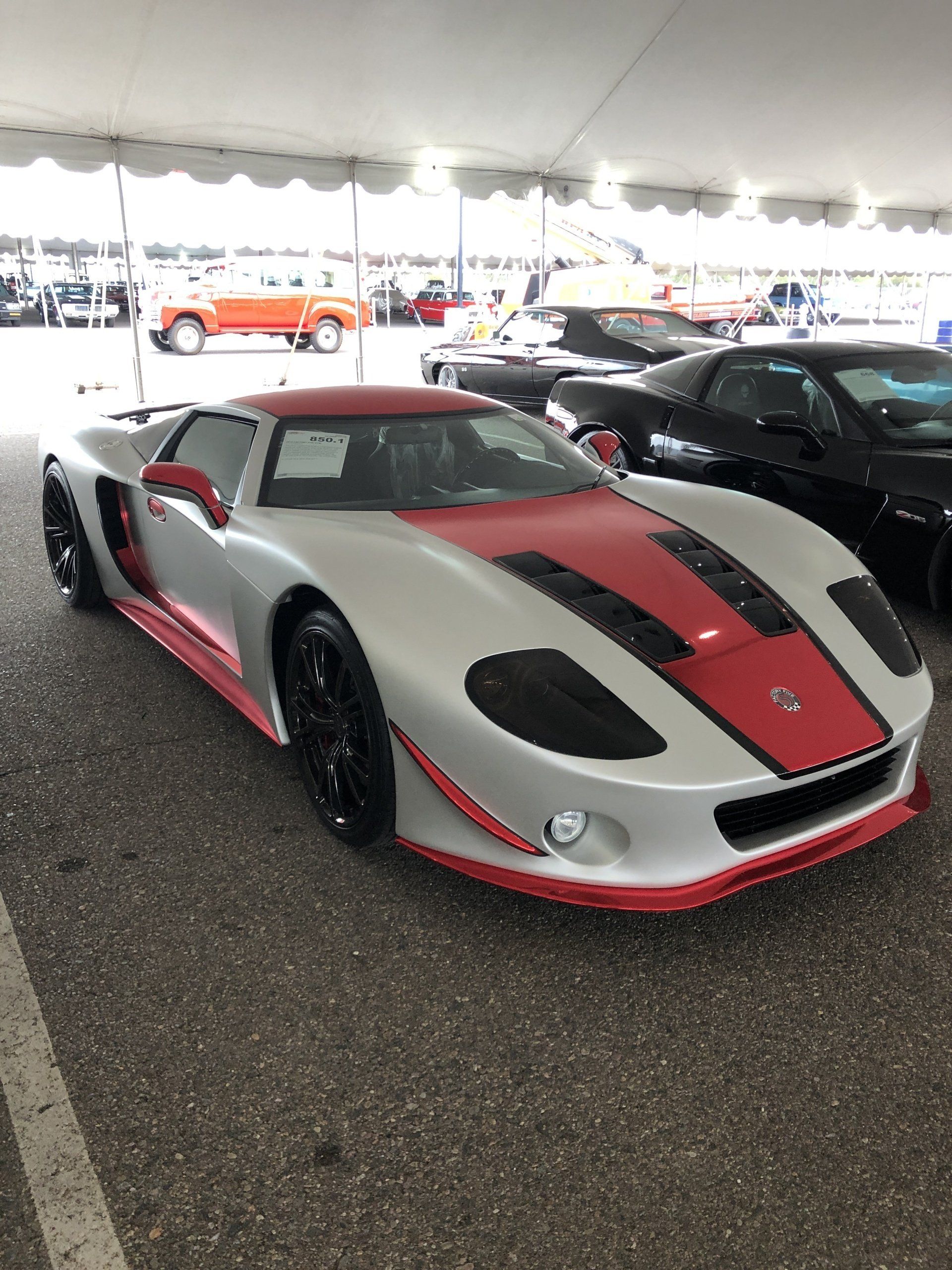 a silver and red sports car is parked under a tent .