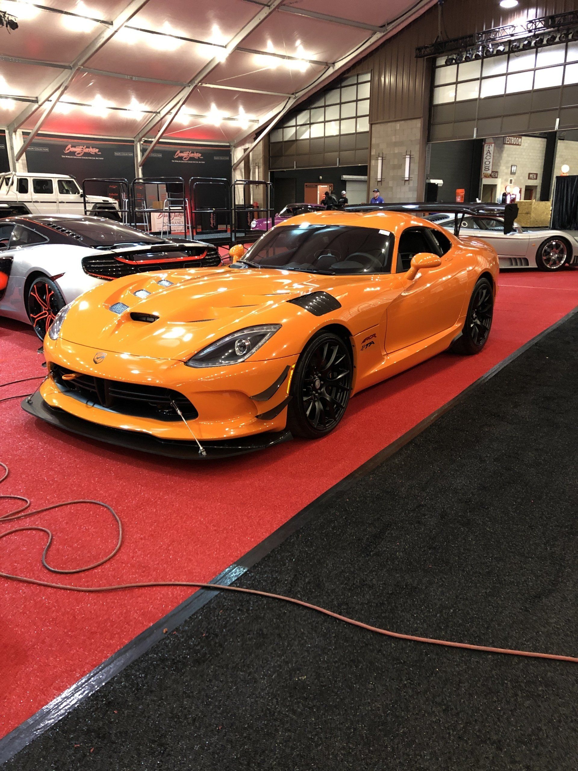 a yellow sports car parked on a red carpet at a car show .