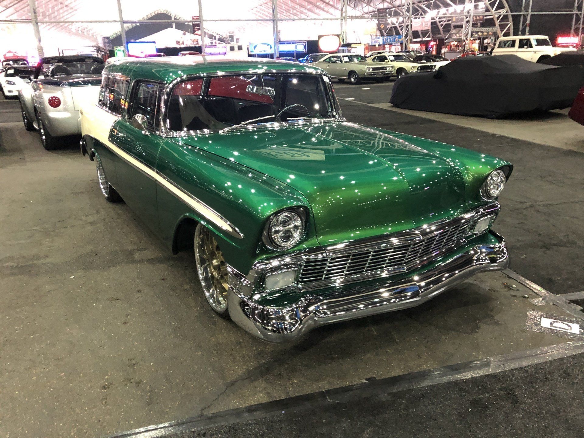 a green car parked in a parking lot with other cars .