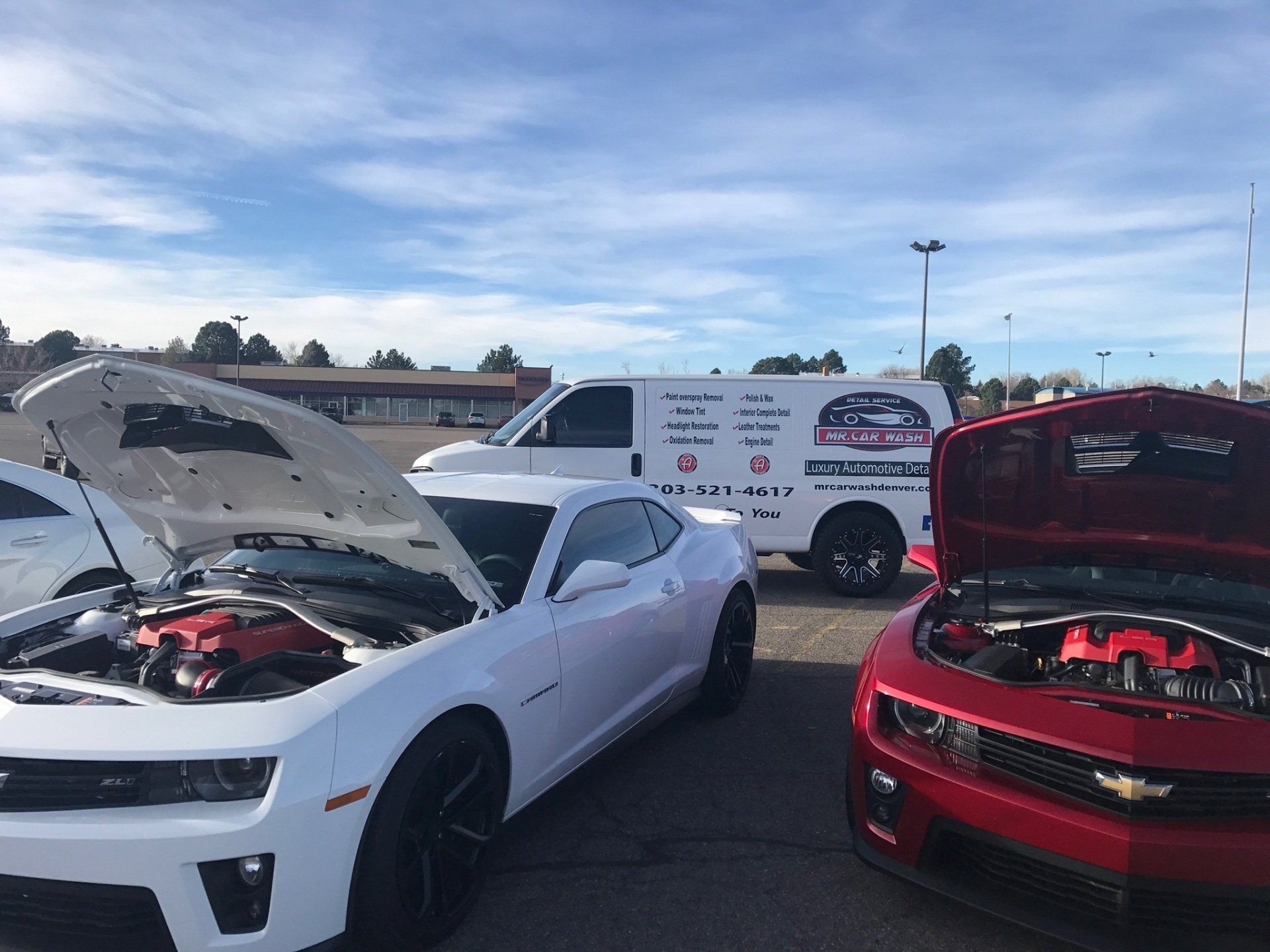 white and red cars parked next to each other with their hoods open .