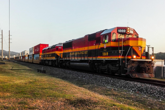 A red and yellow train is going down the tracks.