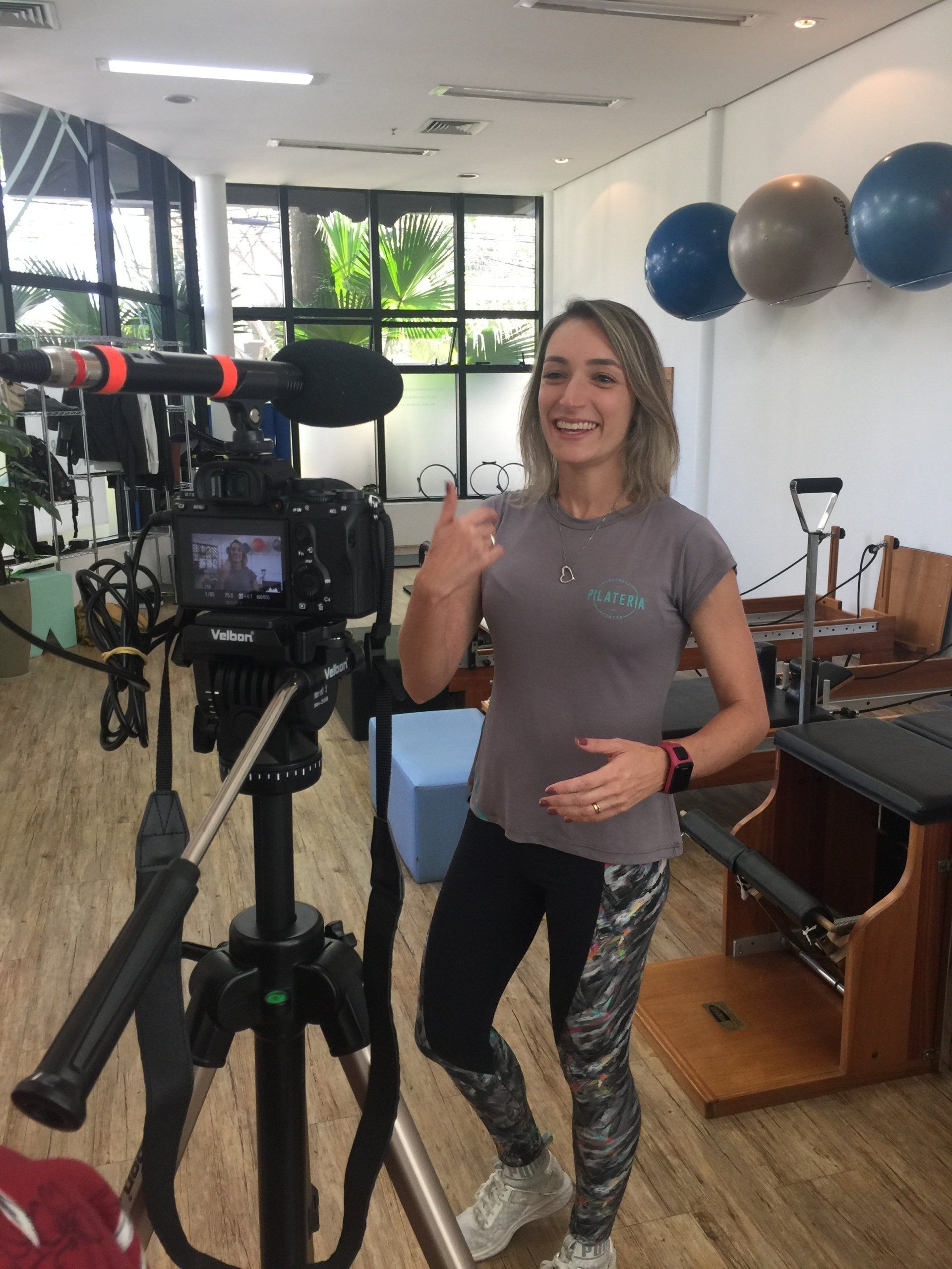 Mulher vestida com roupa de ginástica filmando com uma câmera 
