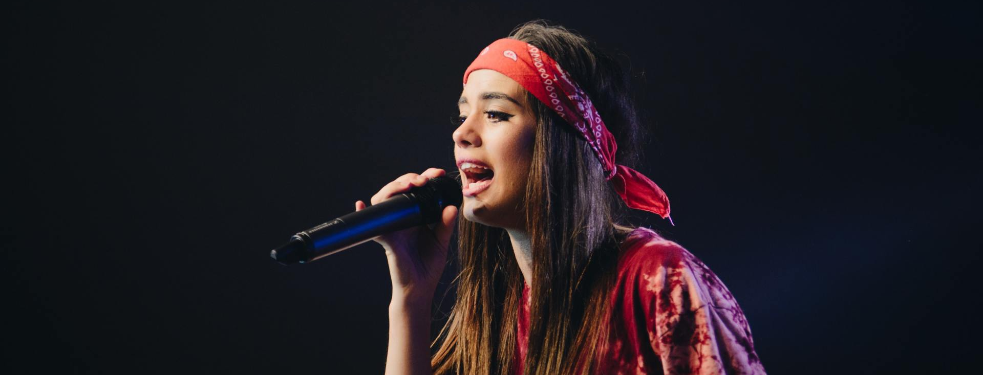 Música com direito autoral liberado Uma mulher usando uma bandana vermelha está cantando em um microfone.