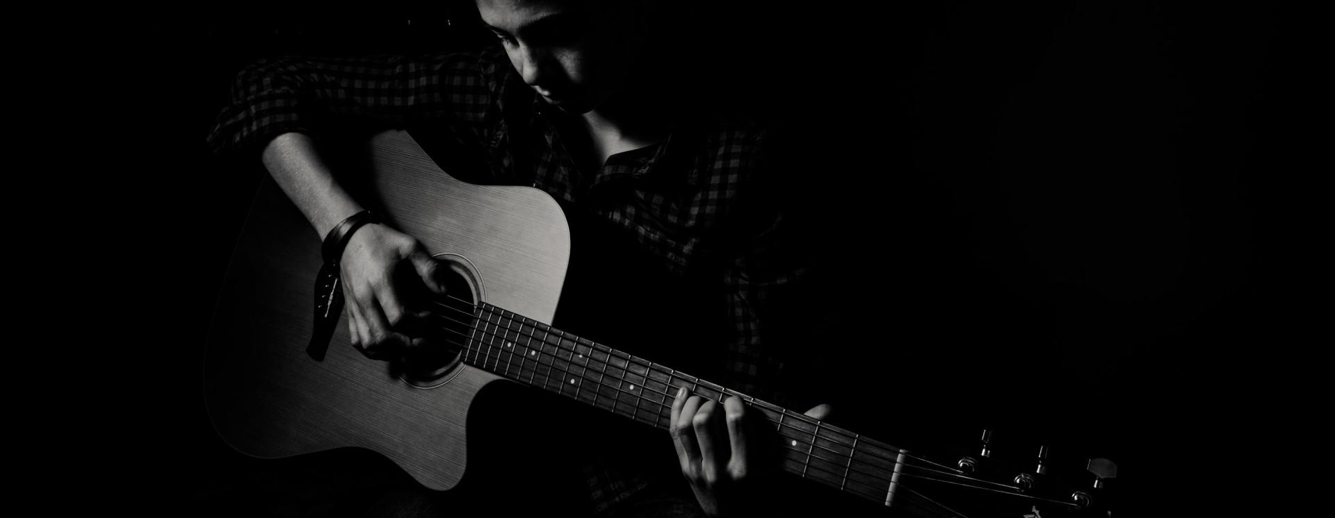 Música Royalty Free Um homem está tocando um violão em uma foto em preto e branco.