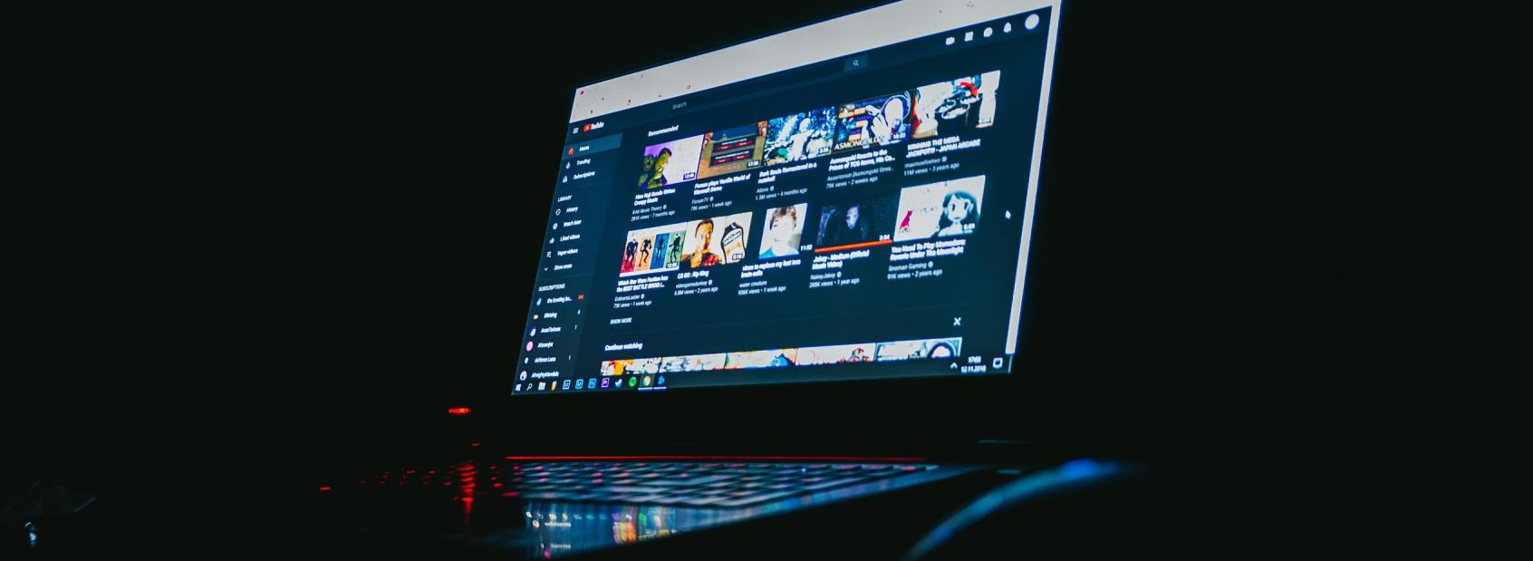 Um laptop está sobre uma mesa no escuro.