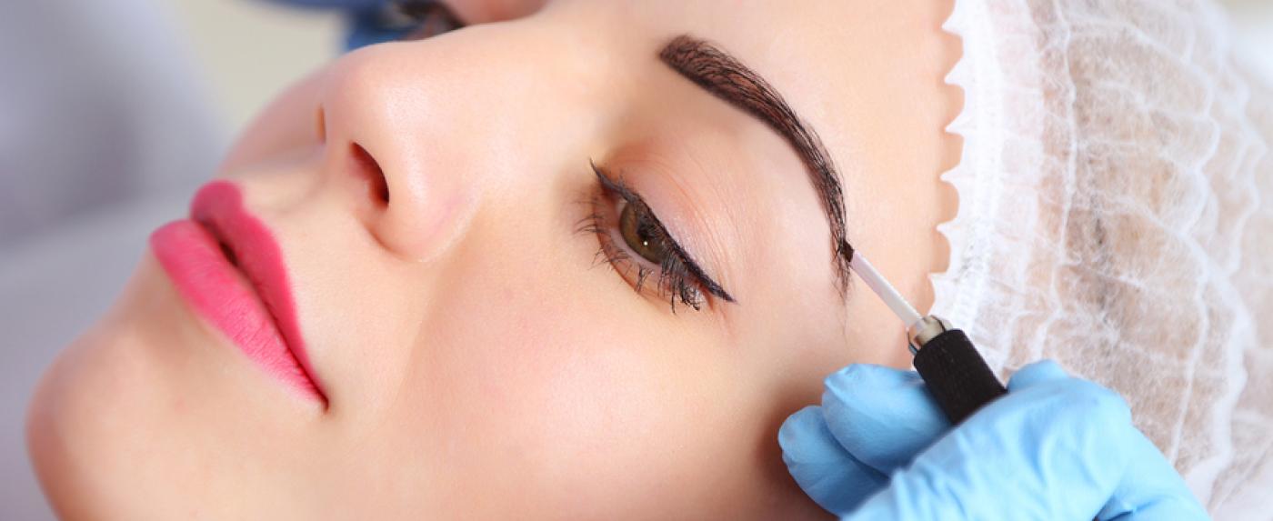 A woman is getting permanent makeup on her eyebrows.