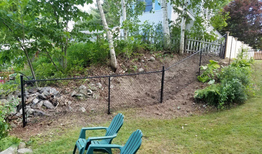 two green chairs are sitting in the grass in front of a fence .